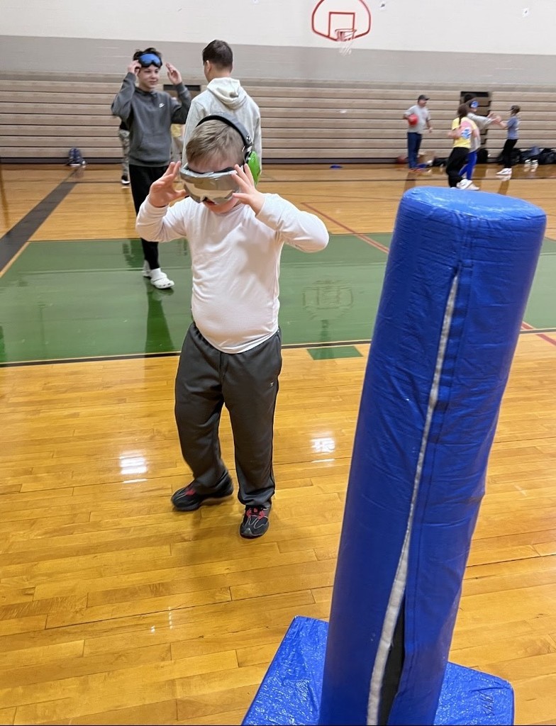 Students walk in gym with vision impairment goggles